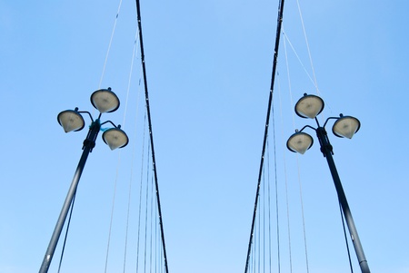 Street lamps under blue sky on the side of suspending bridgeの写真素材