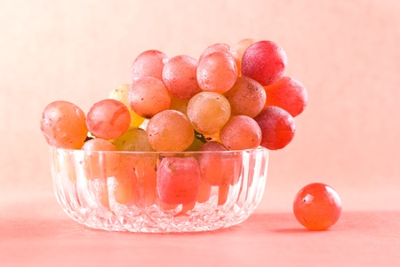 Red grape fruit in glass bowl with red background. の写真素材