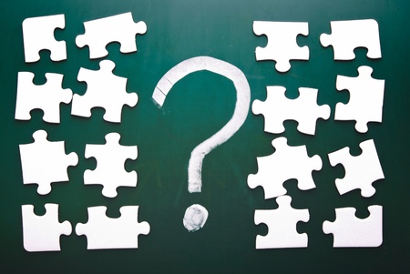 Question mark and puzzle pieces on blackboard