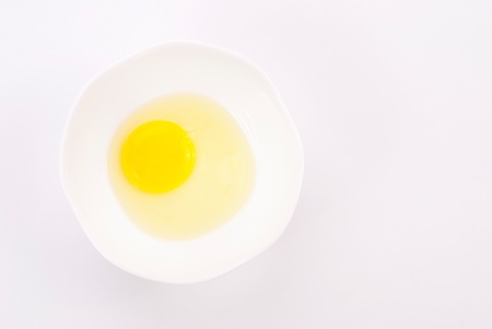 Fresh egg yolk in white bowl on white background の写真素材