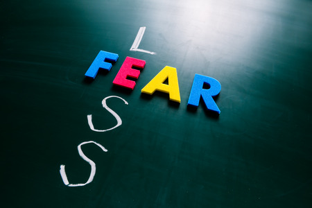 Colorful word fear and writing word less crossing on blackboardの写真素材
