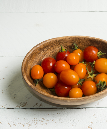 Fresh red and yellow cherry tomatos cooking on wooden board.の写真素材