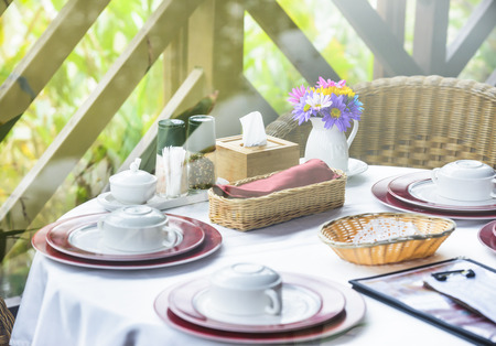 Table set for dinner in a restaurant or bistro with dinnerware and linen and a small vase of...
