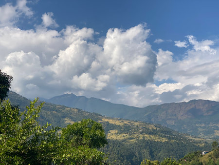Mountain landscape with green trees and blue sky with white clouds.の写真素材