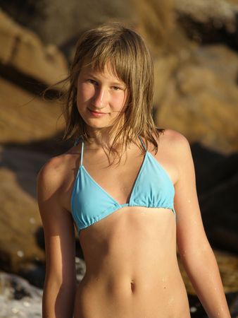 The beautiful young girl with a mysterious smile costs against rocks. Shot on a belt.の写真素材
