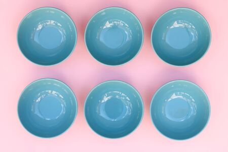 Six blue plates on pink table arranged in a row.の写真素材