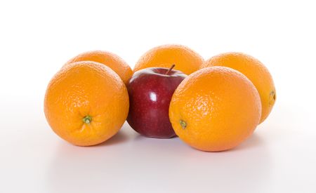 A red apple hemmed in by a group of oranges to illustrate the concept of の写真素材