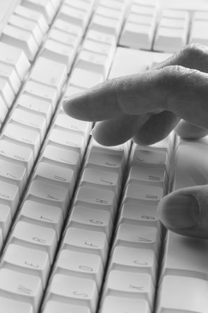 Black and white computer keyboard with fingers, shallow depth of field, focus on handの写真素材