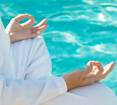 Hands in meditation mudra above water, shallow depth of field, focus on front handの写真素材