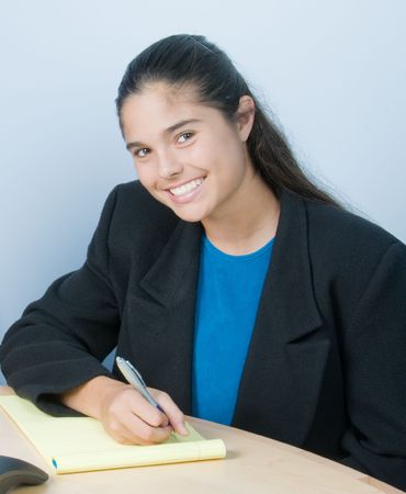 Pretty young woman at a table with pen and notepad, possible businesswoman or studentの写真素材