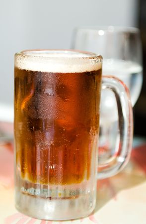 Beer in a frosty mug sitting on a tableの写真素材