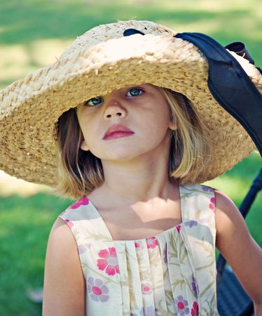 Girl age 4 wearing large straw hat and flowered dress outdoorsの写真素材