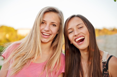 Teen girl best friends laughing and having fun outdoors
