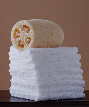 Natural loufah and stack of white towelettes on a mahogany shelf  の写真素材