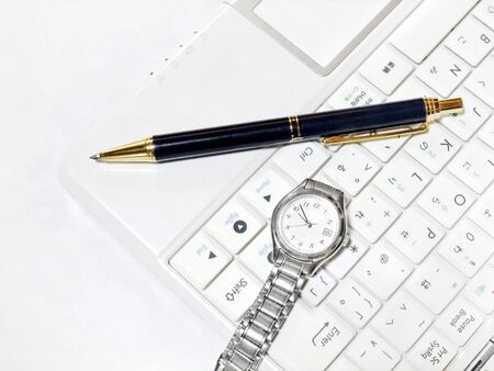 Watch and pen placed on a personal computerの写真素材