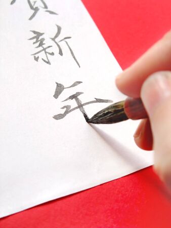 Writing a greeting for the New Year's card with a brushの写真素材
