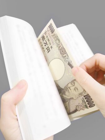 Japanese banknotes sandwiched between booksの写真素材