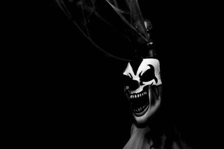 A creepy mask grins with a skeleton behindの素材