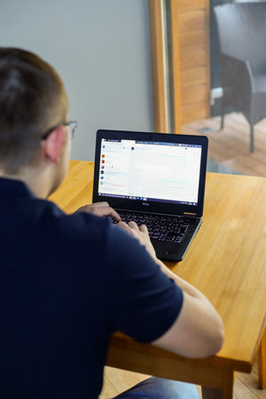 young man using laptop computer at home office, rear view, horizontal