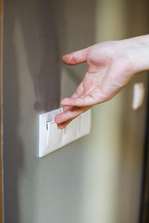 Woman's hand turning on a light switch in a hotel room.の写真素材