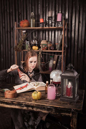 Young beautiful witch read a book at Halloweenの写真素材