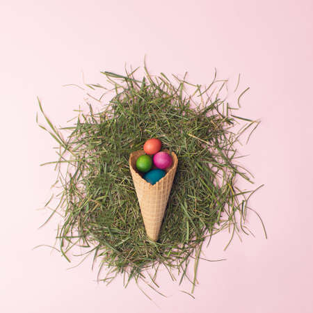 Easter colorful eggs in brown cornet on grass.