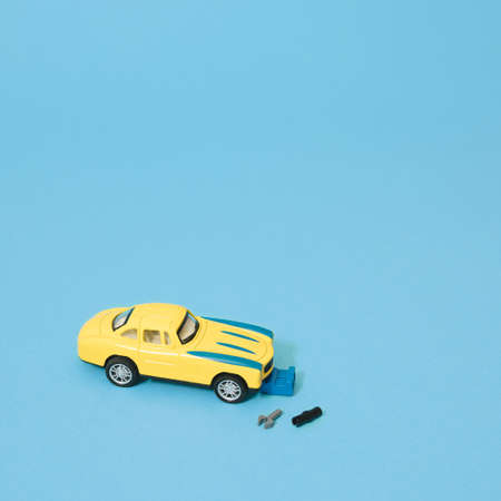 Metal toy yellow classic car and auto mechanic with tools. Blue background. Minimal composition.の写真素材