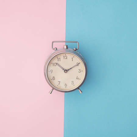 Metal old clock on blue and pink background. Copy space. Minimal concept.の写真素材