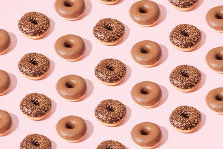 Chocolate donuts on a pink background. Pattern.