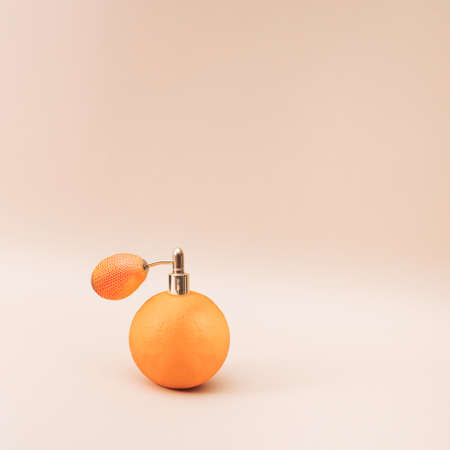 An orange with a perfume pump on it. Beige background.の写真素材