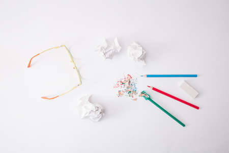 Three wooden crayons. Green, blue and red with yellow glasses and crumpled paper on a white background.の写真素材