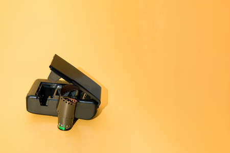 An old open black photo camera from which a film strip comes out. Yellow gold background.の写真素材