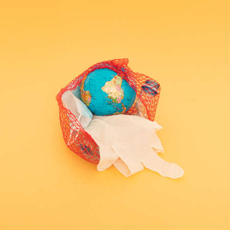 Globe, plastic bottle, blue surgical face mask and white glove in a nylon red bag. Golden...