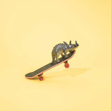 Triceratops on skateboard. Minimal design. Yellow background.の写真素材