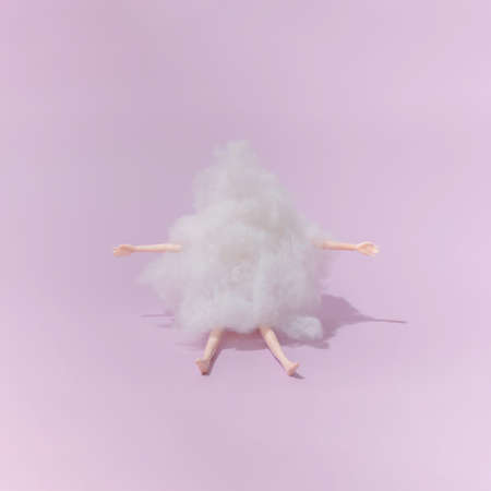 Plastic toy doll covered with wool on purple background. Minimal composition.の写真素材