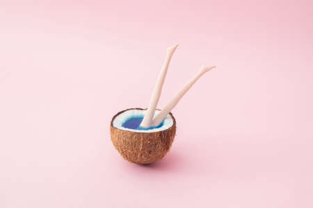Half a coconut with blue water and plastic doll legs protruding from the coconut.の写真素材