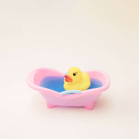 Yellow duck in a pink tub with blue water.の写真素材
