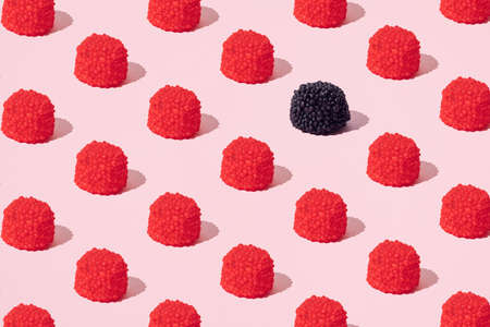 Red and black candies in the shape of blackberries and raspberries. Minimal pattern. Pink...
