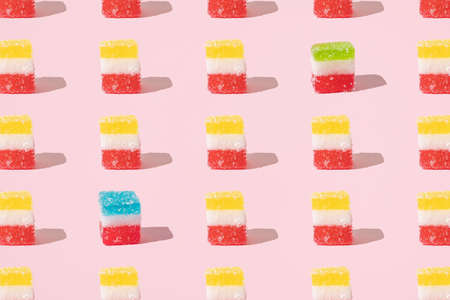 Green cube shaped candies with sugar crumbs. Pink background. Minimal design. Sweet scene with colorful candies.の写真素材