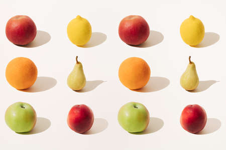 Arranged red apple, orange, green apple, yellow lemon, yellow pear and red peach on a light...