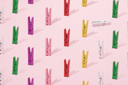 Small wooden colorful pegsfor loundry and paper on a pink background. Minimal design and pattern.