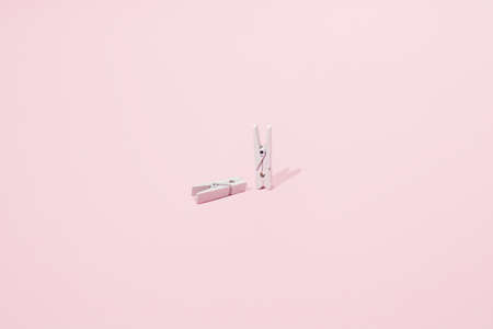 Two white clips on a pink background. One stands and the other is laid. Minimal design.の写真素材