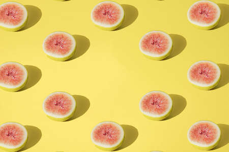Arranged yellow fig half cutted on pastel background. Minimal design. Pattern. Copy space.