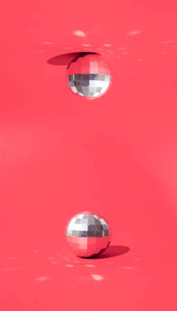 Shining silver disco balls on the floor and ceiling. Minimal New Year's in Christmas design on a red background.の写真素材