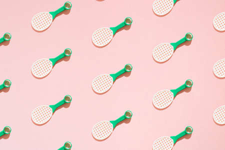 Tennis rackets toys with a green handle. Pink background. Minimal pattern.の写真素材