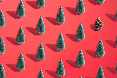 Arranged green New Year and Christmas tree with brown cone on a red pastel background. Pattern.の写真素材