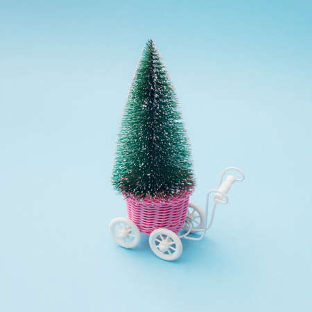 New Year Christmas  tree in a shopping cart on blue paste background. Minimal design.の写真素材