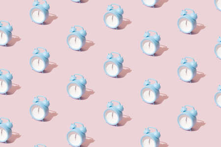 Small blue modern plastic clock with hands on twelve o'clock. Midnight new year Christmas scene on pink pastel background.の写真素材