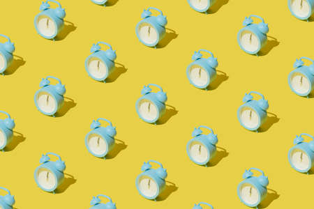 Small blue modern plastic clock with hands on twelve o'clock. Midnight new year Christmas scene on yellow pastel background.の写真素材