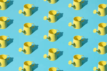 Small yellow flower watering can on a blue pastel background. Pattern.